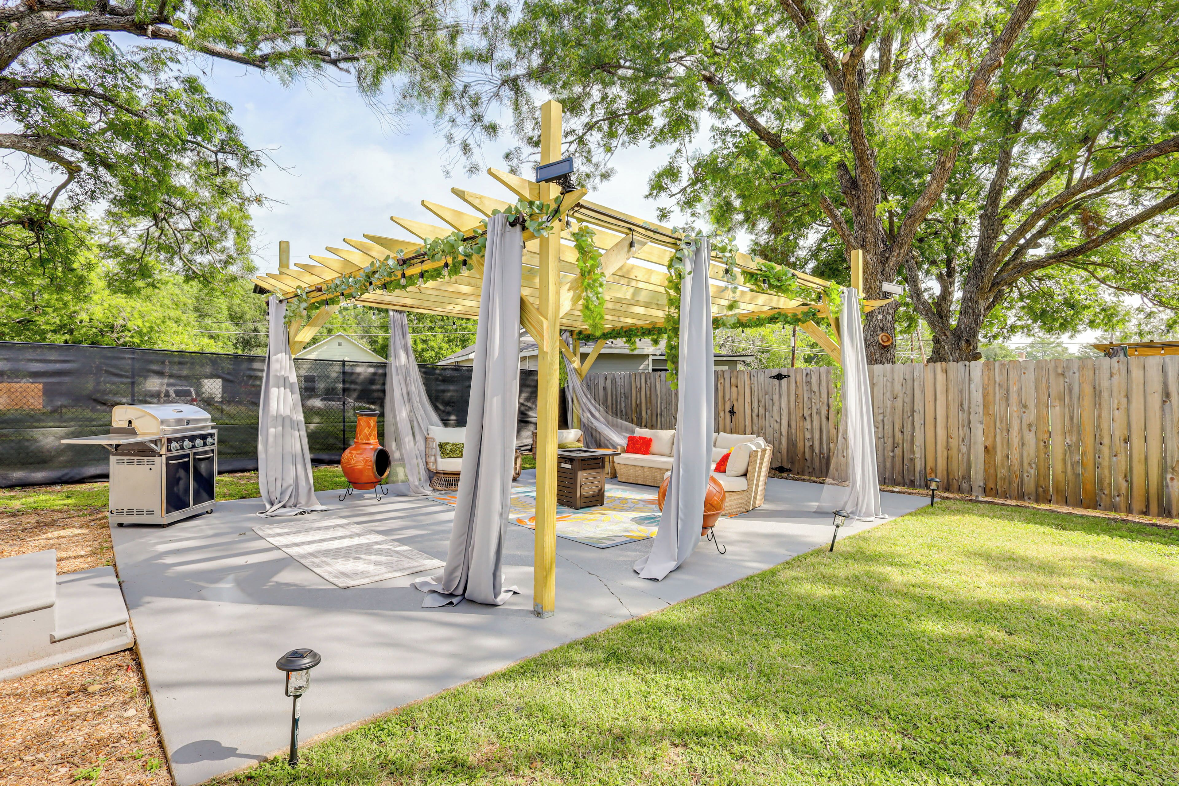 A backyard patio with a pergola, outdoor furniture, and a grill.