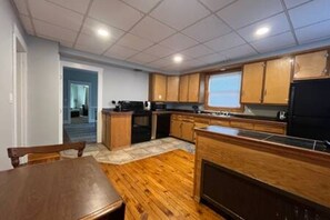 Una cocina compacta con armarios de madera, una isla central y un comedor con mesa y sillas.