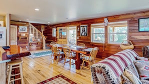 L’intérieur d’un chalet en bois comprend un coin repas, un canapé et un escalier.
