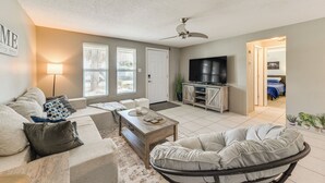 A living room with a sofa, coffee table, and a TV. There is a door leading to another room. - Beach Time + Pool Vibes! Port Charlotte Hideaway (Port Charlotte)