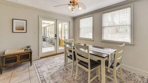 A dining area with a table and chairs, a ceiling fan, and large windows with blinds. - Beach Time + Pool Vibes! Port Charlotte Hideaway (Port Charlotte)