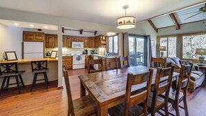 A spacious kitchen with wooden cabinets, a dining area with a large wooden table and chairs, and a cozy living area with a sofa and a lamp. - 1/4 Mi to Golf & Skiing! Sugar Mountain Getaway (Banner Elk)