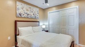 A bedroom with a large bed, a nightstand, a wall-mounted lamp, and a door with a panel design. - 3 Mi to Lookout Mtn! Gem w/ Fire Pit + Fenced Yard (Phoenix)