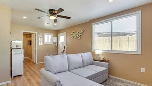 A living room with a grey sectional sofa, a ceiling fan, and a large window with blinds. - 3 Mi to Lookout Mtn! Gem w/ Fire Pit + Fenced Yard (Phoenix)