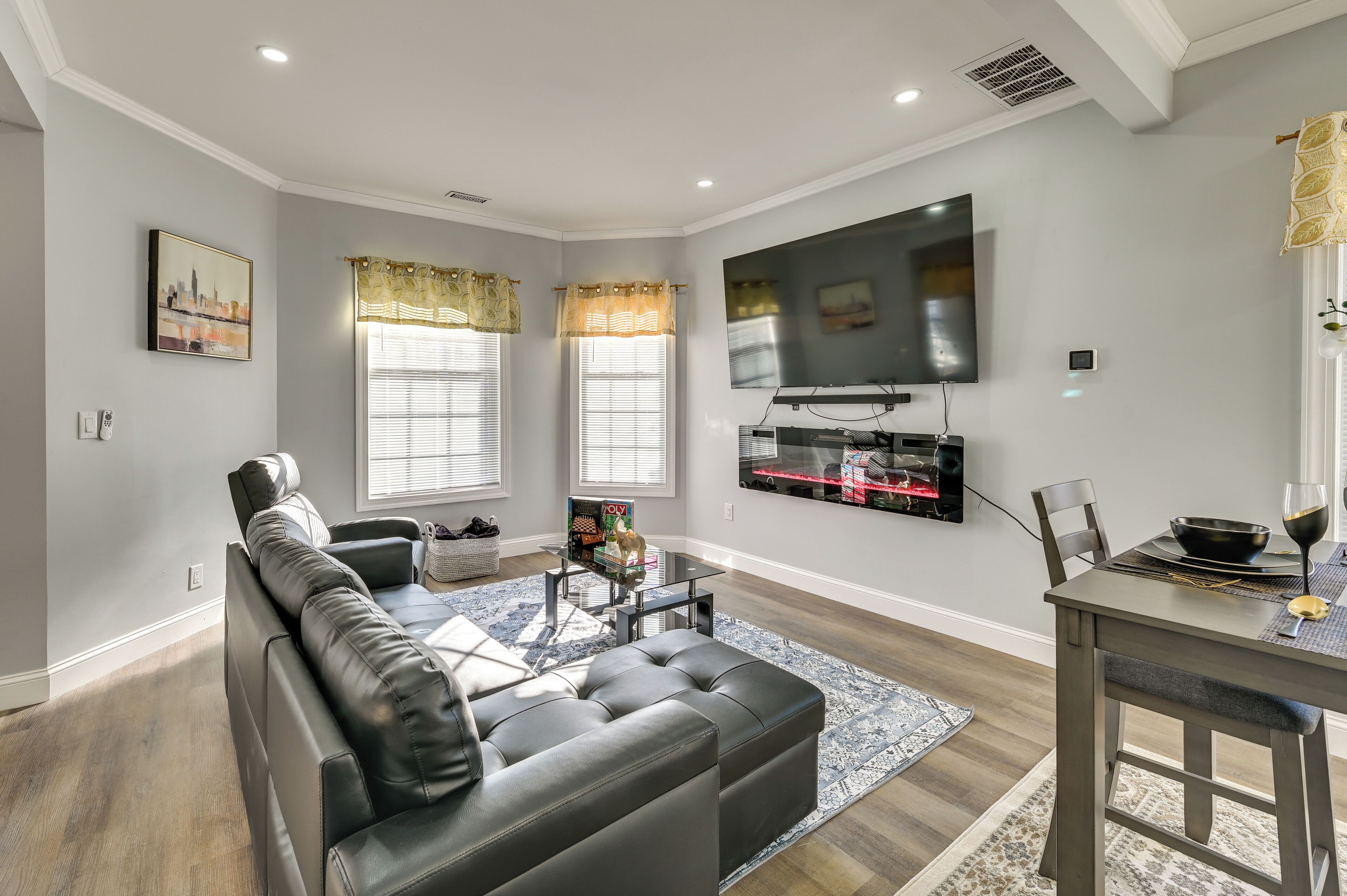 A modern living room with a gray sofa, a coffee table, and a dining area with a table and chairs.