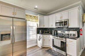A modern kitchen with white cabinetry, stainless steel appliances, and a black backsplash. - Walk to Park: Modern Apt 2 Mi to Union College! (Schenectady)