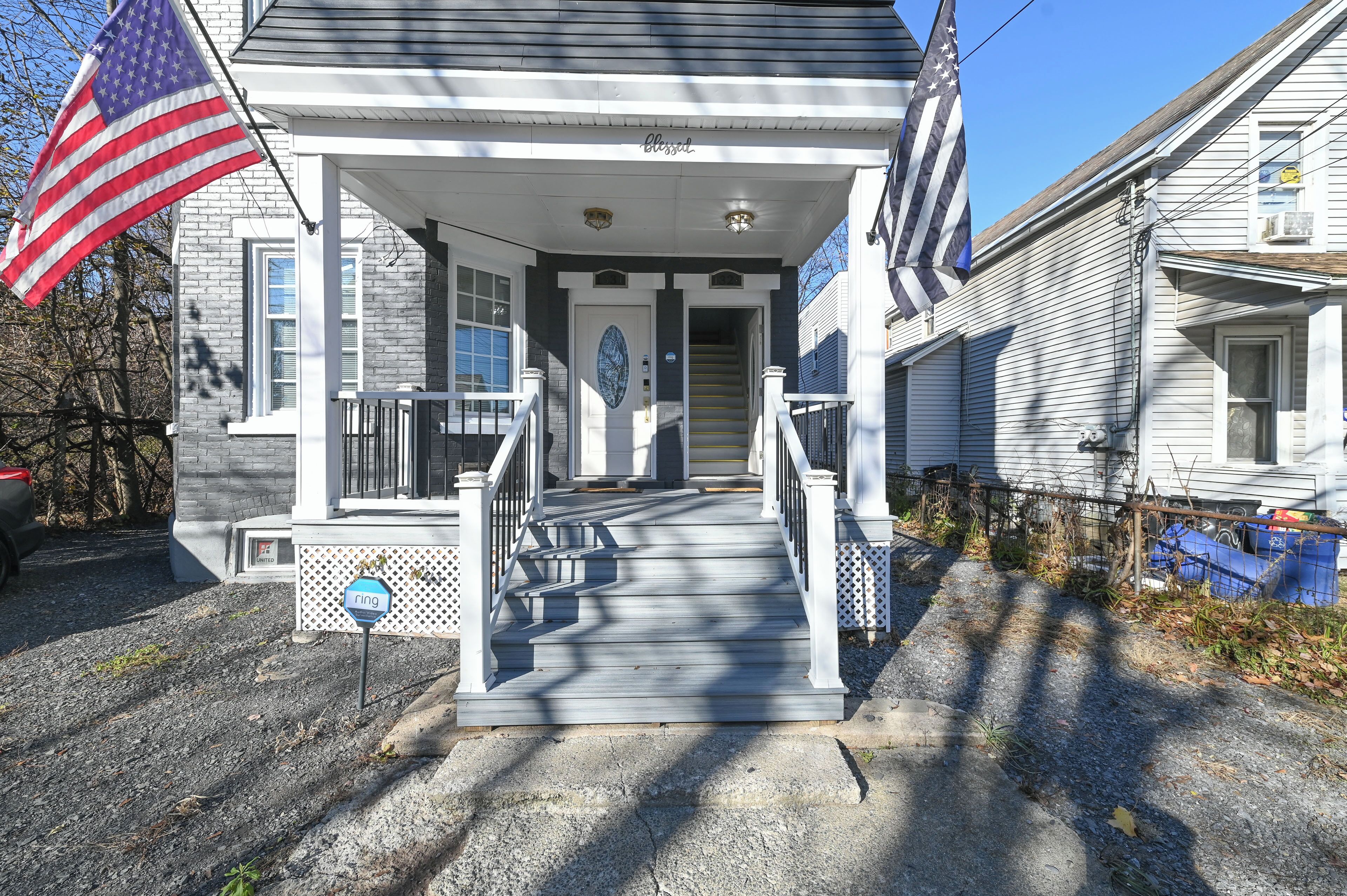 A two-story house with a porch, a front door, and a staircase leading to the entrance.