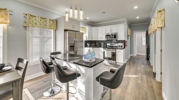 A modern kitchen with white cabinets, a central island with bar stools, stainless steel appliances, and pendant lighting. - Walk to Park: Modern Apt 2 Mi to Union College! (Schenectady)