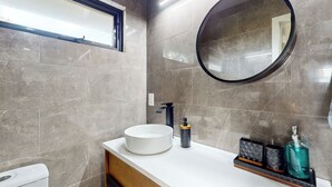 A modern bathroom with a round mirror, a white sink, and a black faucet. - 'bamboo Hideaway' in Cardiff w/ Outdoor Space (Cardiff-by-the-Sea)