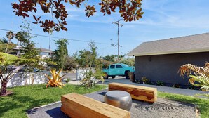 A landscaped outdoor area with wooden benches and a decorative metal sphere. - 'bamboo Hideaway' in Cardiff w/ Outdoor Space (Cardiff-by-the-Sea)