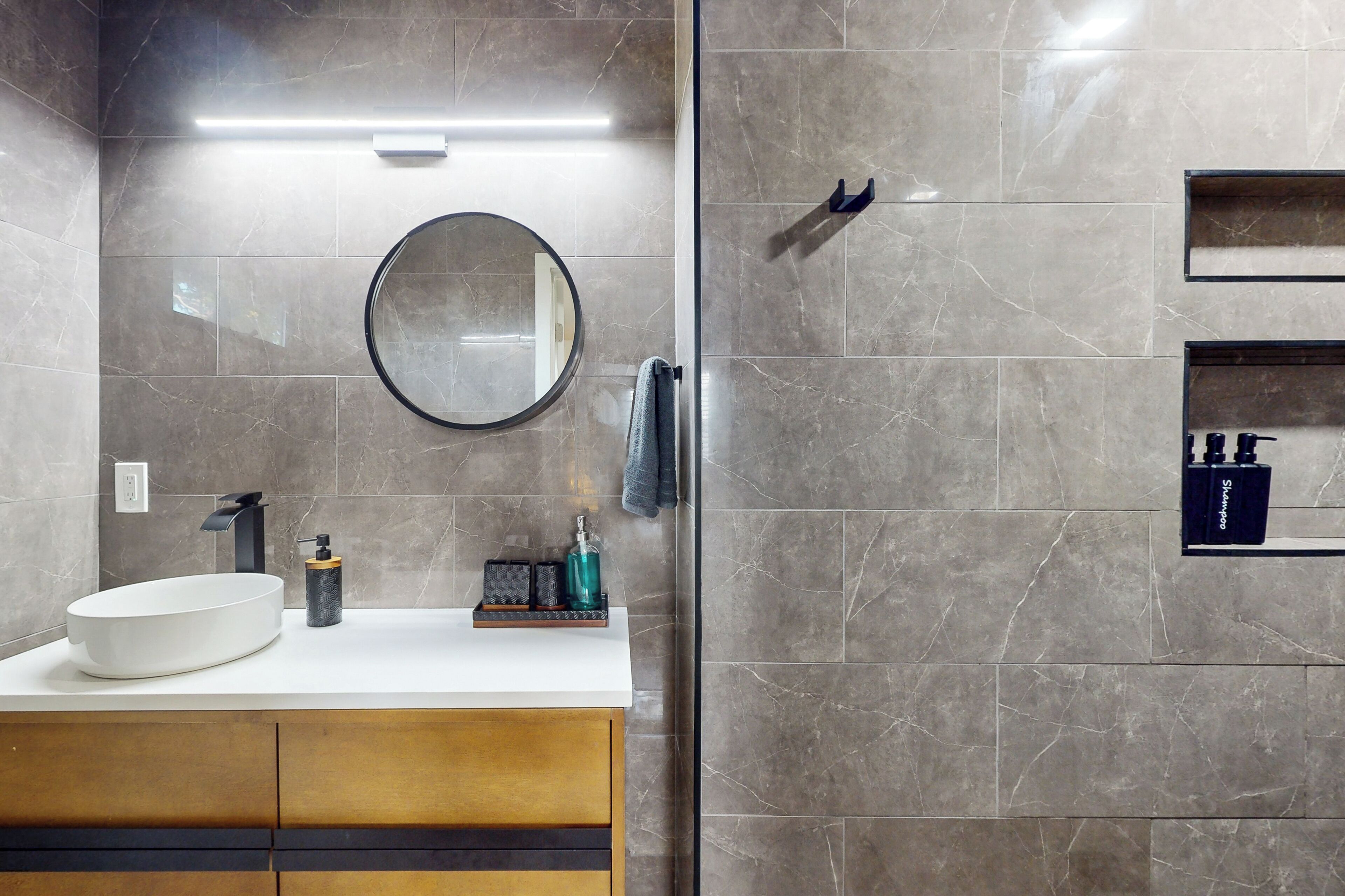 A modern bathroom with a large oval sink, a round mirror, and a towel rack.