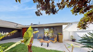 A modern house with a patio area featuring two wooden chairs and a bench. - 'bamboo Hideaway' in Cardiff w/ Outdoor Space (Cardiff-by-the-Sea)