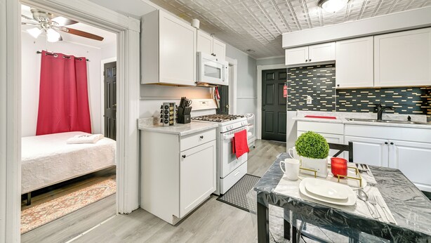 Une cuisine compacte avec des meubles blancs, un four à micro-ondes, une cuisinière et un coin repas avec une table dressée pour deux personnes.
