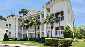 A multi-story hotel with balconies, a well-maintained lawn, and palm trees. - 2BR Condo on Golf Course w/ Pool & Tennis Court (Myrtle Beach)