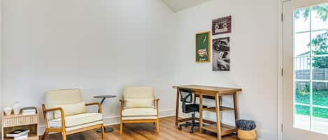 A room with two chairs, a small table, a wooden desk, and a bookshelf.