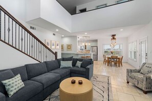 Una sala de estar moderna con un sofá seccional, una mesa de centro redonda y una escalera.