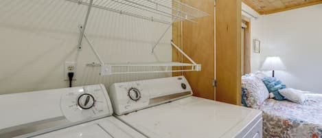 A laundry area with two washing machines and a drying rack.