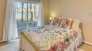 Une chambre avec un grand lit, une fenêtre avec des rideaux et une vue sur des arbres et un lac.