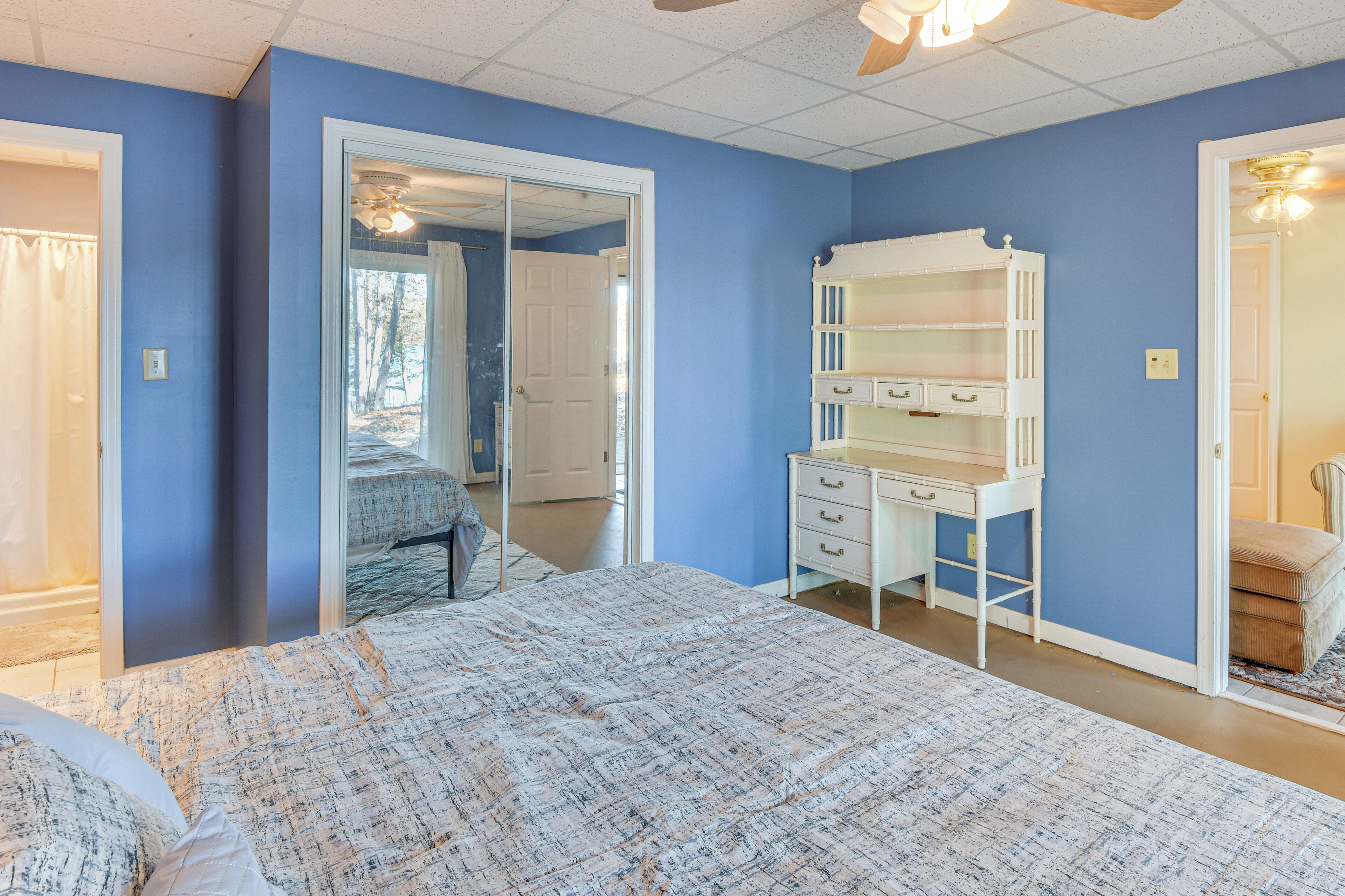 A bedroom with a large bed, a dresser, and a mirror.