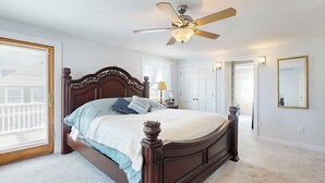 Une chambre à coucher avec un grand lit, un ventilateur de plafond et une vue sur l’extérieur par une fenêtre.