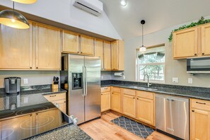 Una cucina moderna con mobili in legno, elettrodomestici in acciaio inox, piani di lavoro in granito e lavastoviglie integrata.