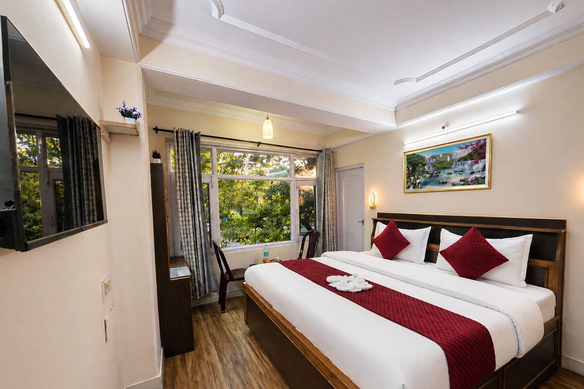 Een hotelkamer met een groot bed, een raam met gordijnen, een bureau en een stoel.