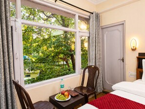 A hotel room with a large window, a bed, a chair, a table with fruits, and a door. - Sapphire B&B Near Mall Road Shimla (Shimla)