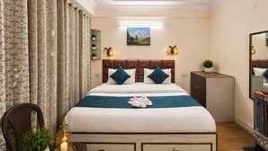Ein Hotelzimmer mit Bett, Schminktisch, Spiegel, Wandlampe und einem Gemälde.
