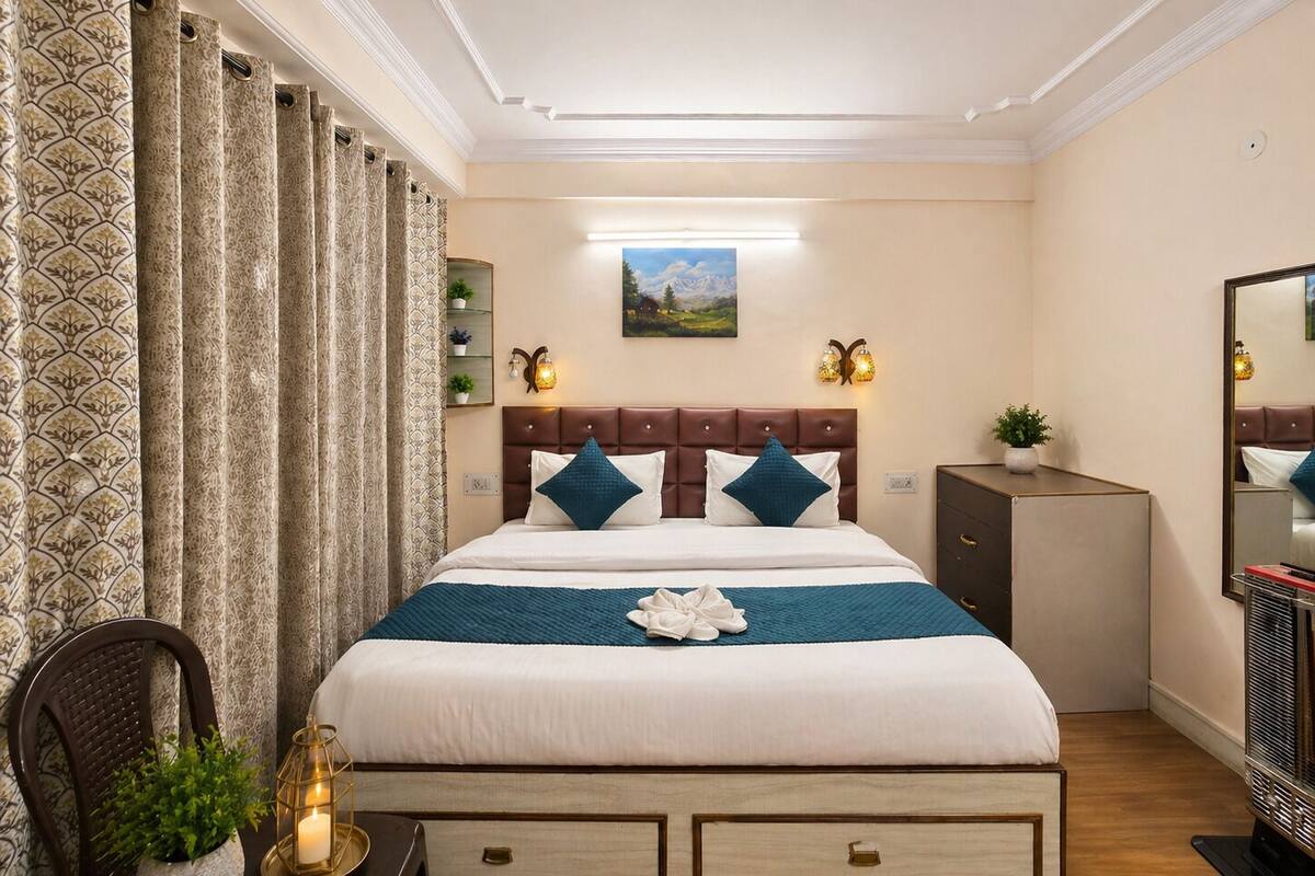 Een hotelkamer met een bed, een dressoir, een spiegel, een wandlamp en een schilderij.