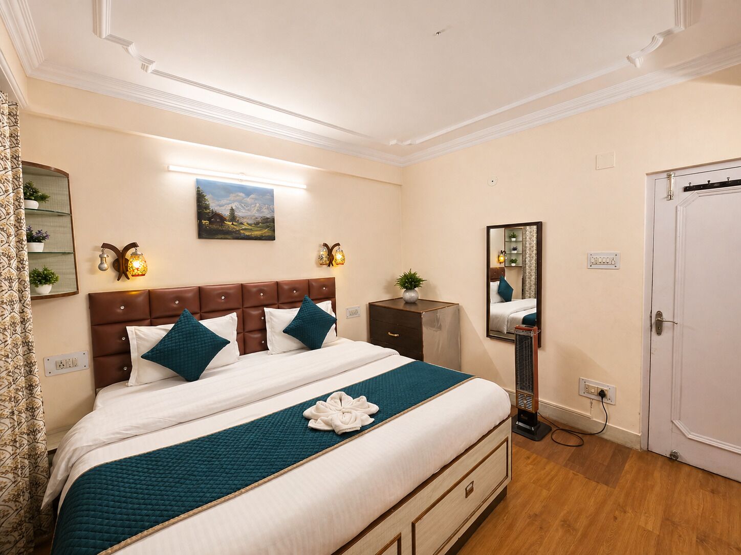 A hotel room with a bed, a mirror, a heater, and a door.