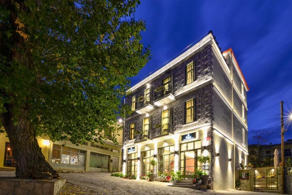 Un edificio de piedra con varios pisos, ventanas grandes y una entrada bien iluminada.