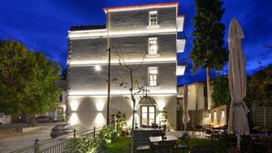 A two-story building with a balcony and outdoor seating area. - Megaro Gioule (Voio)