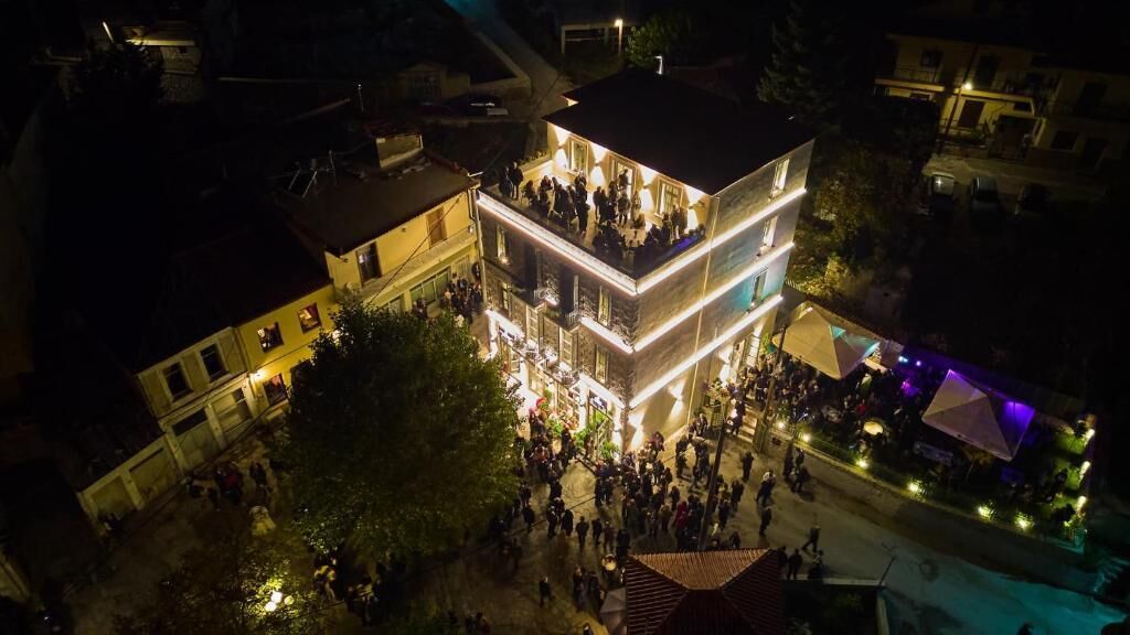 Un edificio de varios pisos con un balcón y una multitud de personas reunidas afuera.