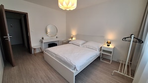 A modern bedroom with a large bed, bedside tables, a mirror, and a hanging light fixture.