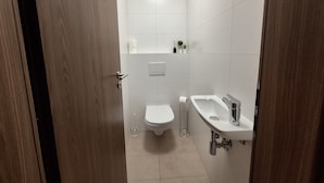 A modern bathroom with a toilet, sink, and shower area.
