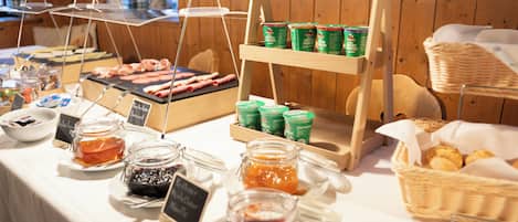 Een buffet met diverse soorten eten, waaronder potten jam, een kaasplateau en een presentatie van brood.