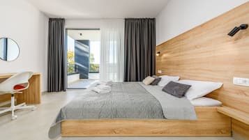 Una habitación de hotel moderna con una cama grande, cabecera de madera, escritorio con silla y vistas al exterior.