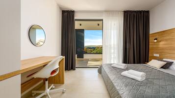 Une chambre d’hôtel moderne équipée d’un lit, d’un bureau avec une chaise, d’un miroir et offrant une vue sur l’extérieur.