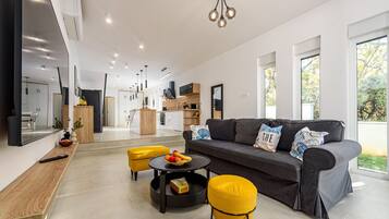 Un salon moderne avec un canapé gris, des poufs jaunes et une table basse ronde.