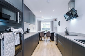 A modern kitchen with a central island, dark cabinetry, and a large window. - M22 | Near Airport | Parking | WiFi | 15% Off (Wythenshawe)