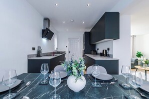 A modern dining area with a marble table, multiple wine glasses, and a centerpiece. - M22 | Near Airport | Parking | WiFi | 15% Off (Wythenshawe)