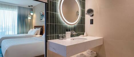 A hotel room with a bed, a bathroom with a sink, and a mirror.