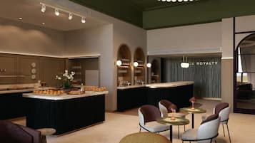 Uma cozinha moderna com ilha central, área de estar com mesas redondas e um bar com piano.