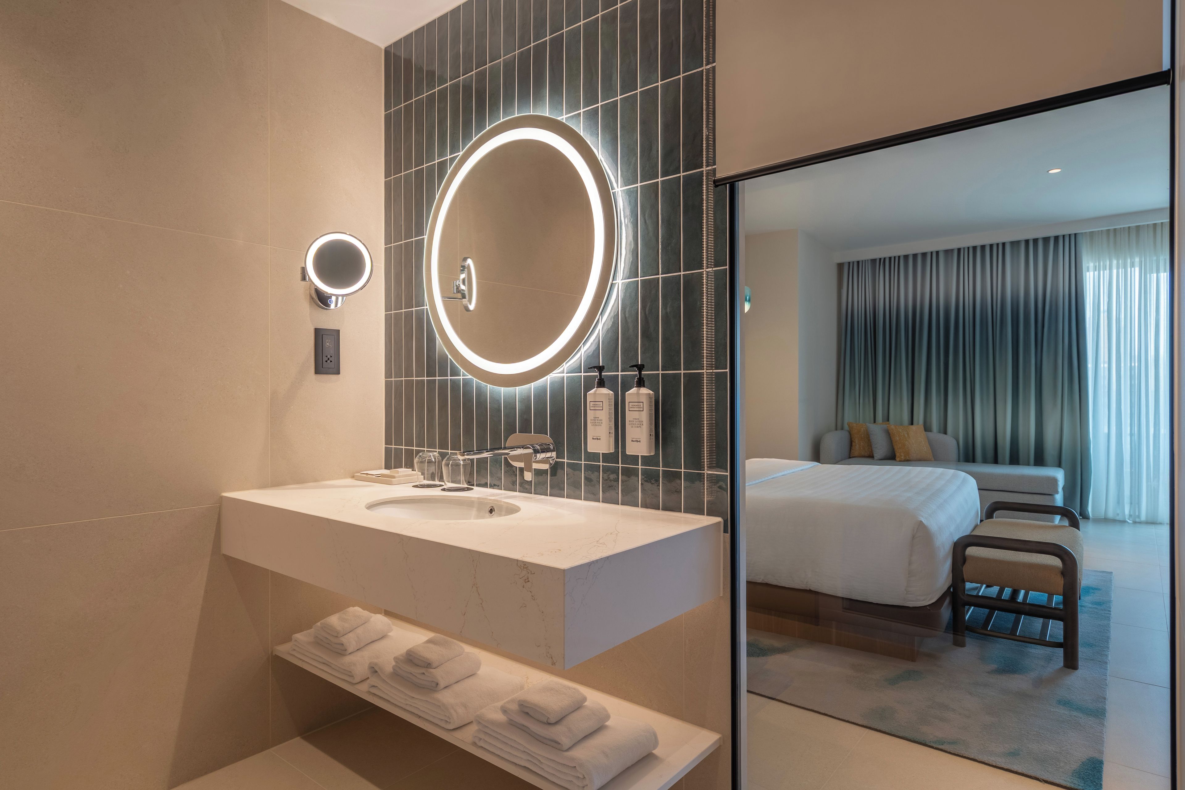 A modern bathroom with a large mirror, a sink, and a towel rack.