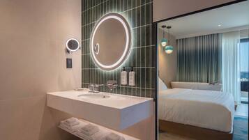 A hotel bathroom with a large mirror, a sink, and a towel rack.