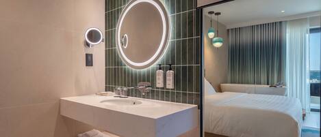 A hotel bathroom with a large mirror, a sink, and a towel rack.