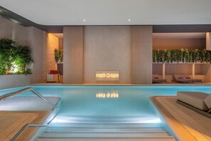 A modern indoor pool area with a clear glass barrier, a spa sign, and lounge chairs. - Hard Rock Hotel Malta (St. Julian's)