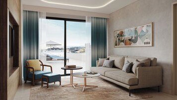 A modern living room with a sofa, armchair, coffee table, and a view of the sea through large windows.