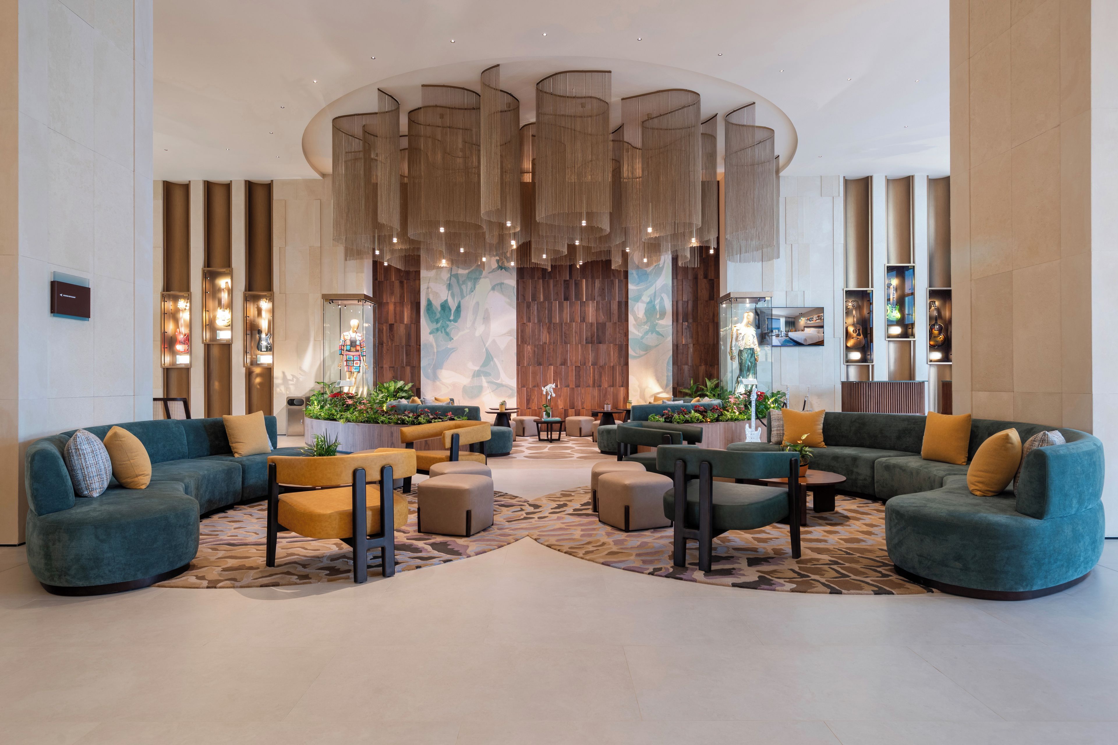 A modern lobby with seating areas, a large decorative wall, and a ceiling with hanging lights.