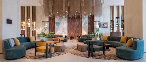A modern lobby with seating areas, a large decorative wall, and a ceiling with hanging lights.